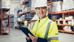 Profissional utilizando tablet para monitorar operações com IoT na logística em centro de distribuição.